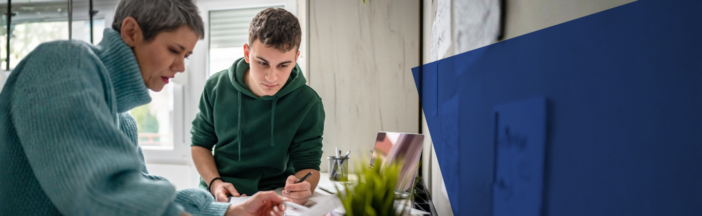 Headerbild Mutter mit Sohn Header Mutter und Sohn sind über einen Tisch gebeugt und haben Unterlagen vor sich