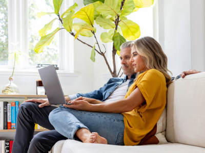 Mann und Frau sitzen auf dem Sofa und haben einen Laptop auf ihrem Schoß