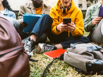 Vier Jugendliche sitzen nebeneinander auf dem Boden 